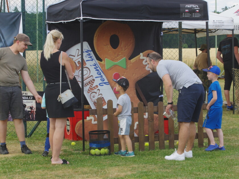 Children playing at outdoor event booth with gingerbread man display and wooden fence game setup