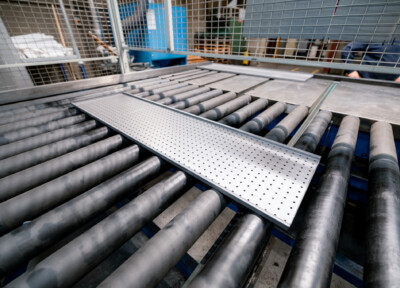 Roller conveyor system with perforated metal platform during assembly in manufacturing facility