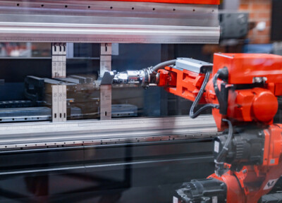 Industrial robotic arm with red gripper positioning metal shelving component near aluminum frame with measurement scale