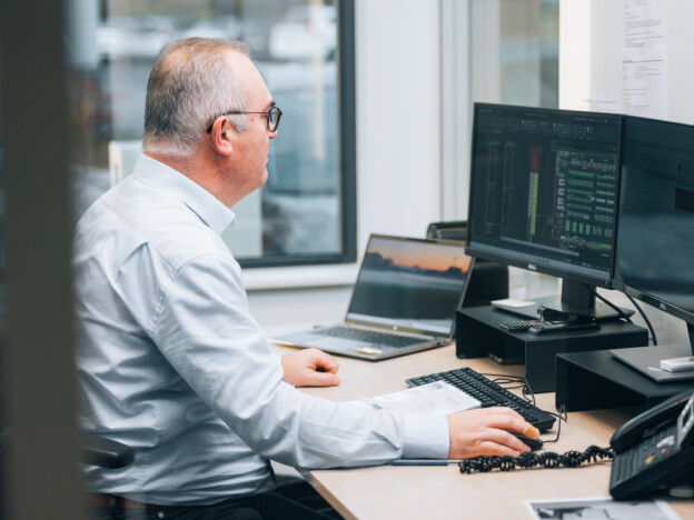 Professional working at computer workstation with dual monitors displaying design software in retail solutions office environment