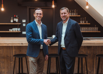 Two business professionals shaking hands at a modern bar counter in a retail environment