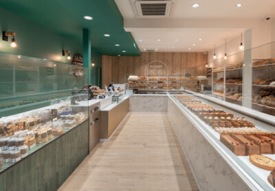 Bakery patisserie retail display with marble checkout counter, open shelving, and glass-fronted cooling cases