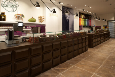 Specialty food retail interior with brown checkout counters, colorful product displays, hanging pendant lights and branded signage