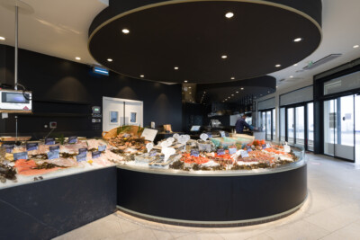 Curved refrigerated seafood display counter with ice, fish and shellfish in specialty food retail setting