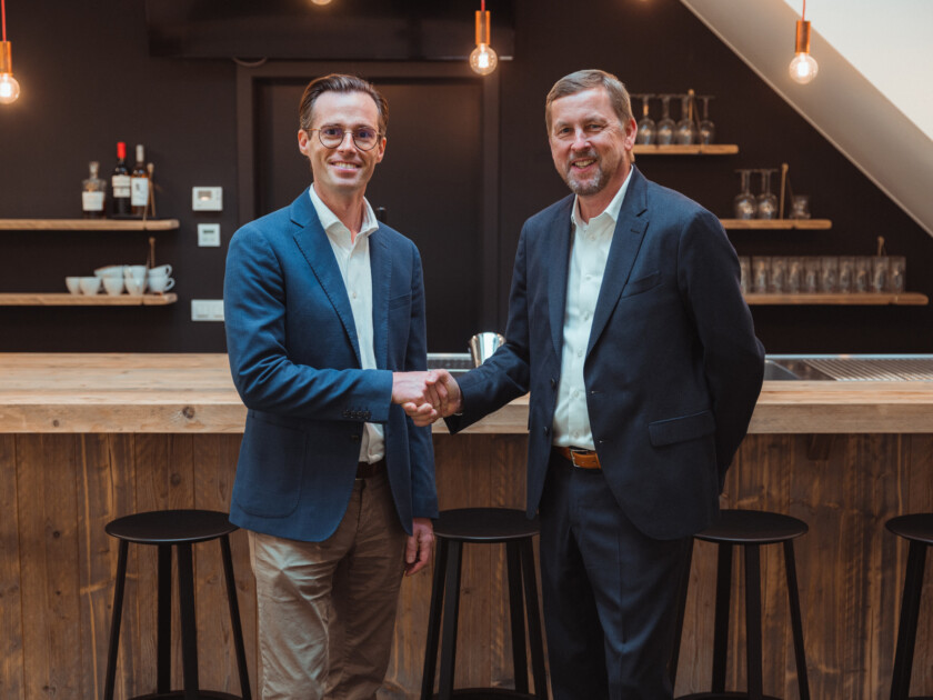 Two business professionals shaking hands at a modern bar counter in a retail environment