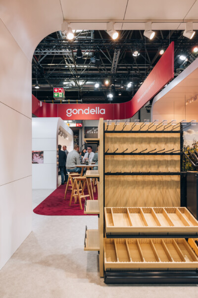 Gondella booth at Euroshop 2023 displaying wooden shelving units with black metal frames and product display stands
