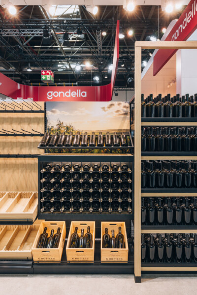 Gondella wine retail display with black wine racks, wooden shelving, and wooden crates showing 6-bottle storage at Euroshop 2023