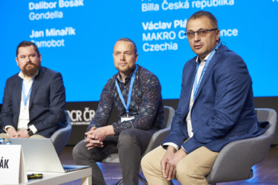 Three professionals at The Retail Summit 2024 panel discussion on stage with blue backdrop