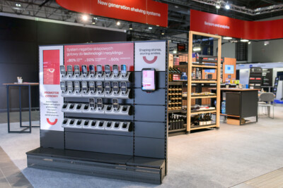 Gondola shelving display with mobile device charging stations at retail trade show, featuring recycling and technology messaging