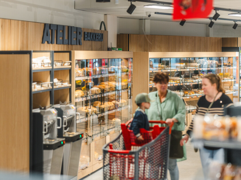 Bakery section with Pitch shelving displaying bread products, customer with red shopping basket, modern retail store interior