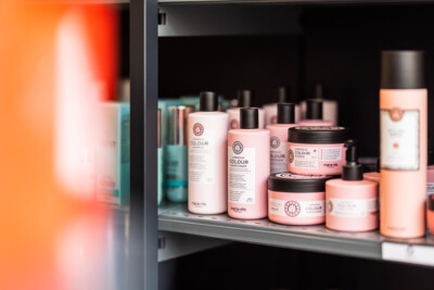 Maria Nila Luminous Colour hair care products displayed on retail shelf with pink and white bottles and jars