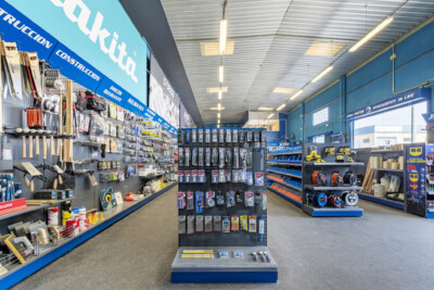 DIY retail store interior with Gondella Pitch shelving, pegboard displays, central fixture with tools and hardware, blue-framed sections displaying fasteners and accessories