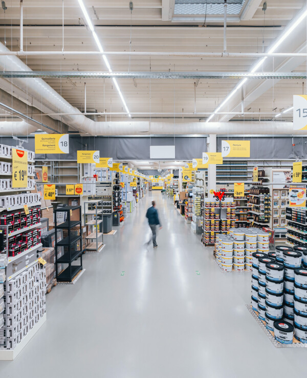 DIY retail aisle with Pitch shelving displaying paint cans, hardware supplies, and building materials under bright warehouse lighting