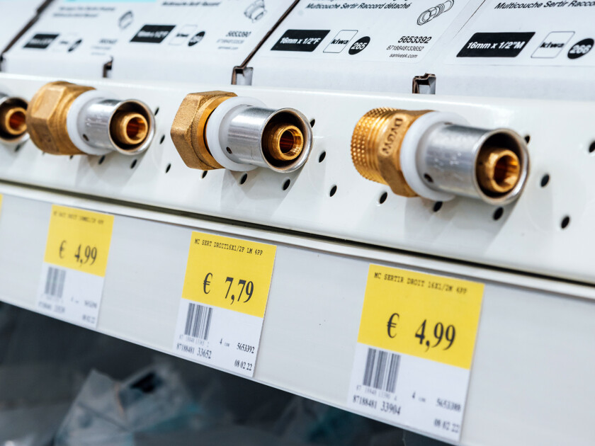 Brass push-fit plumbing connectors displayed on retail shelf with yellow price tags