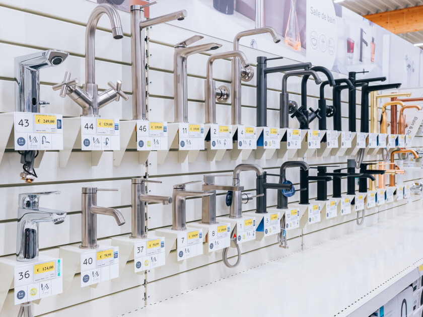 Bathroom faucet display with chrome and matte black taps on retail shelving with product information tags