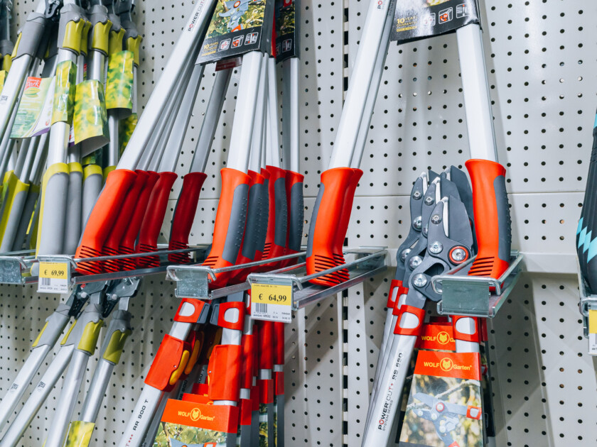 Garden tool display shelf with loppers, pruning saws, and hedge shears in red and orange handles