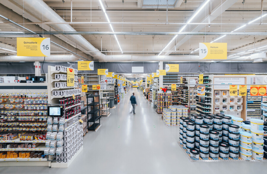DIY retail aisle with Pitch shelving displaying paint cans, hardware supplies, and building materials under bright warehouse lighting