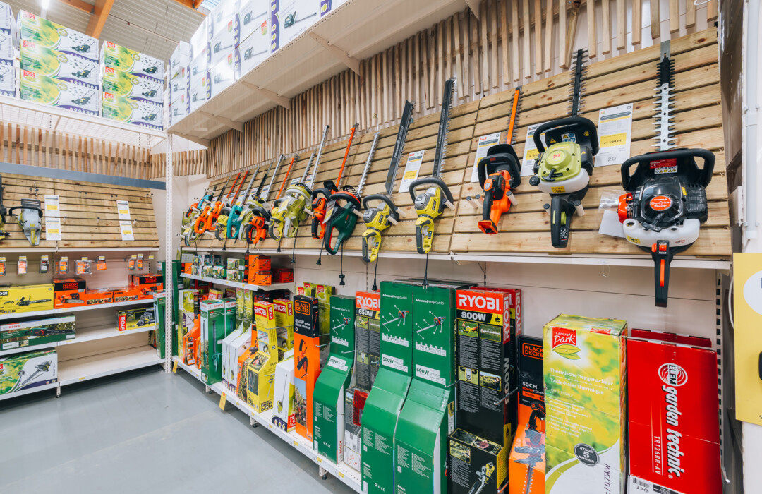 Chainsaw and power tool display with RYOBI branded boxes and hanging chainsaws in DIY retail store