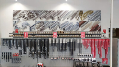 Hardware retail display wall with screws, anchors, and tools organized on shelving and pegboard with product photography backdrop
