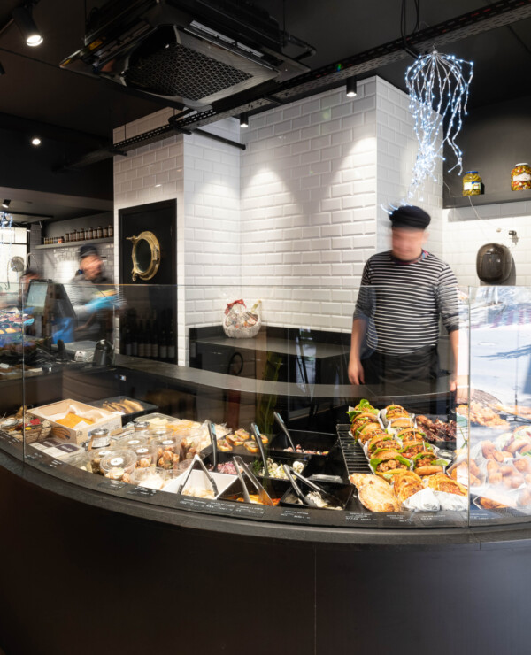 Curved glass cooling counter display with prepared foods and bakery items in specialty food retail environment