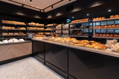 Bakery display with illuminated shelving showcasing bread, pastries and baked goods in specialty food retail environment