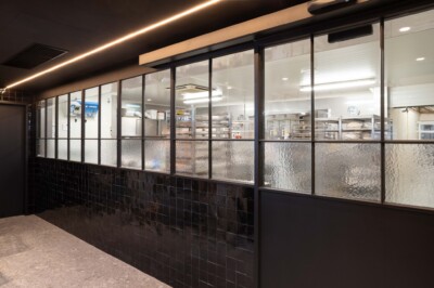 Bakery display with black tile base and glass-fronted shelving units, interior shelves and professional lighting