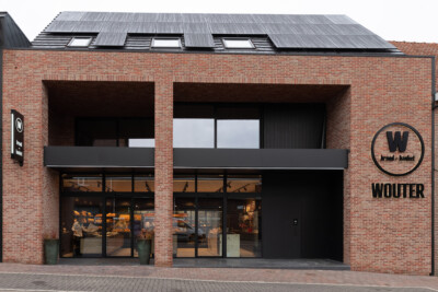 Wouter bakery storefront in Zonnebeke with brick facade, black framing, large display windows, and solar panels on roof