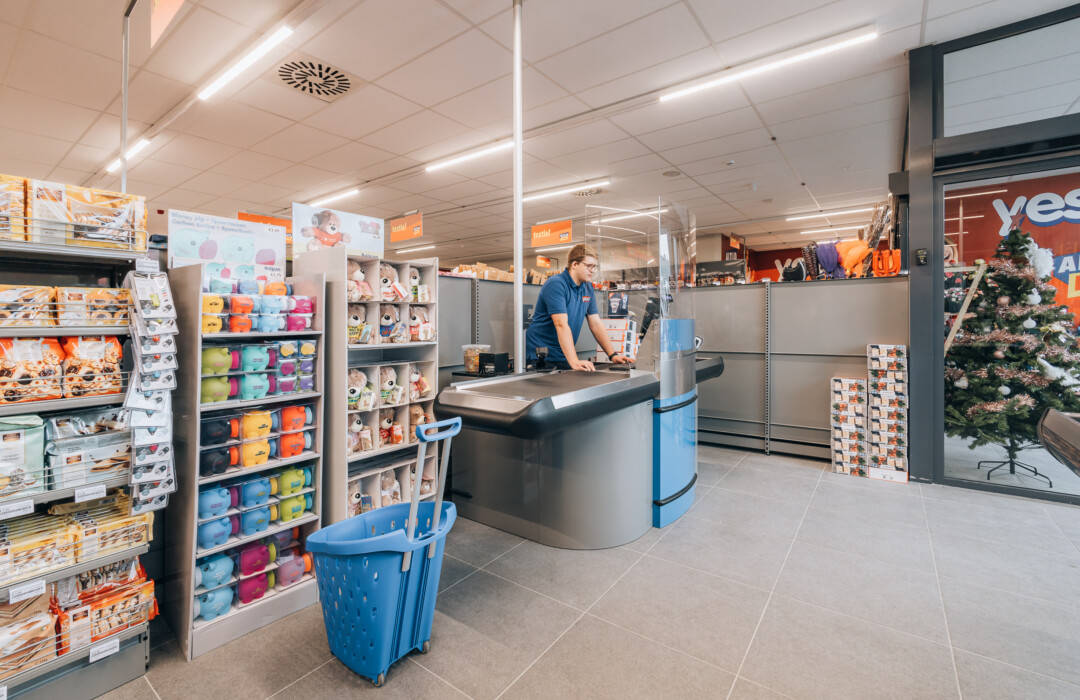Yess discount store checkout counter with blue shelving display of colorful household products and storage containers