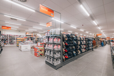 Yess Waregem supermarket textile section with Gondella shelving displaying clothing and accessories