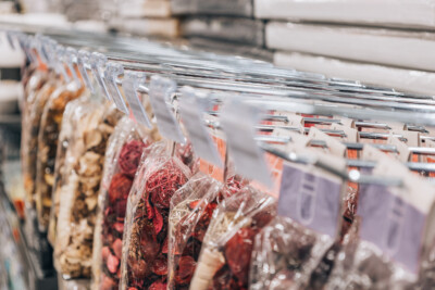 Packaged specialty foods and spices displayed on retail shelving with colorful packaging in reds and earth tones