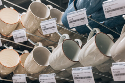 Earthenware mugs with orange trim displayed on retail shelf with price labels €2.49, Yess Waregem store