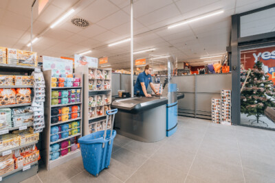 Yess discount store checkout counter with blue shelving display of colorful household products and storage containers