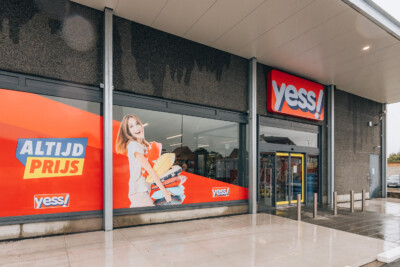 Yess fashion retail storefront with red branding, shelving displays, and entrance in shopping center