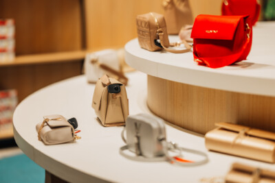 Beige and red leather handbags displayed on white retail display table