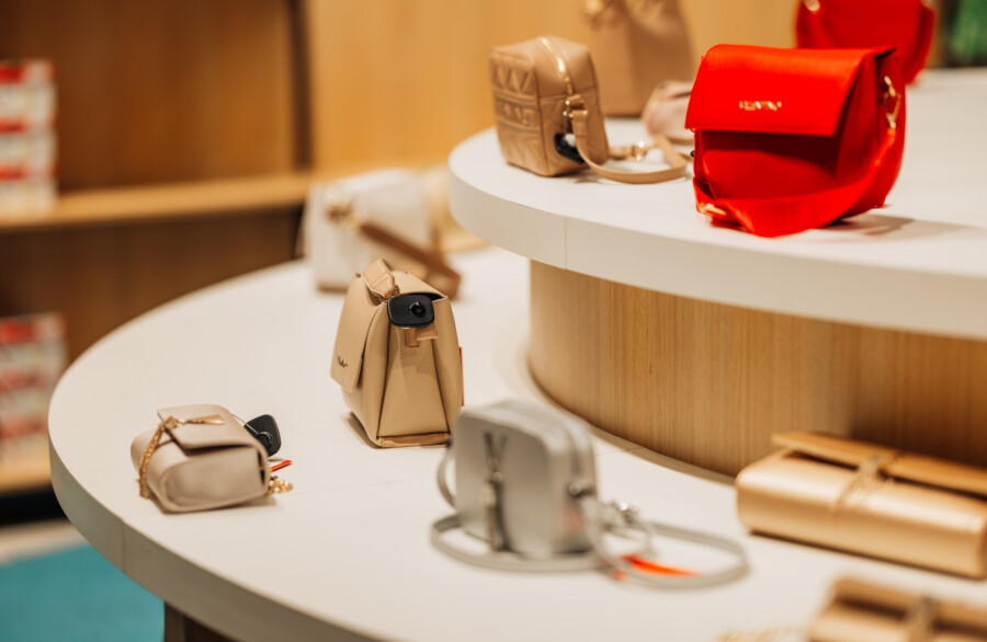 Beige and red leather handbags displayed on white retail display table