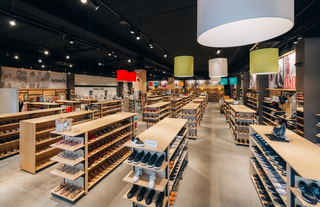 Lachapelle fashion retail store with wooden Pitch shelving displaying shoes, pendant lighting, and customer browsing area
