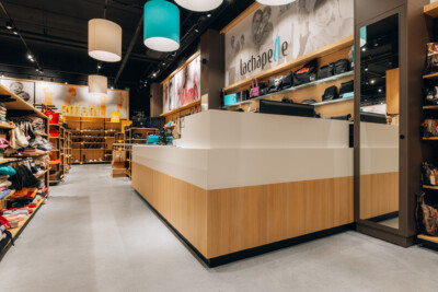 Lachapelle fashion retail store checkout counter with wooden and white design, shelving displays, and turquoise pendant lighting