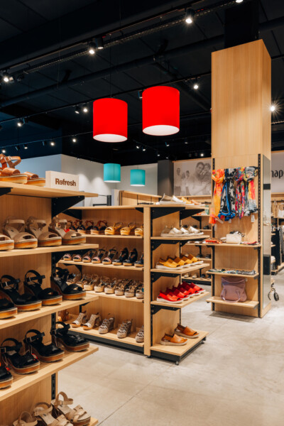 Wooden shelving display with shoes and fashion items in retail store with red pendant lights