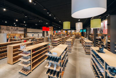 Lachapelle fashion retail store with wooden Pitch shelving displaying shoes, pendant lighting, and customer browsing area