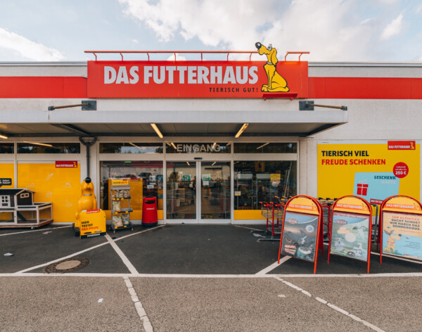 Das Futterhaus pet supply store entrance with yellow and red branding, outdoor display stands, and storefront shelving