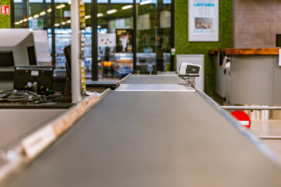 Checkout counter with integrated scanner and conveyor belt in modern retail store with green wall paneling