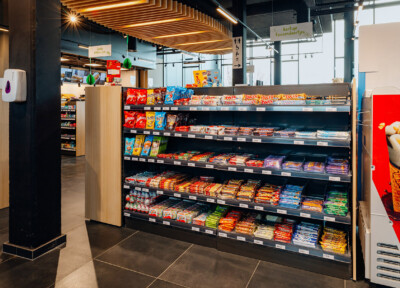 Pitch 25 shelving displaying confectionery and snacks in Delhaize supermarket with illuminated wooden ceiling