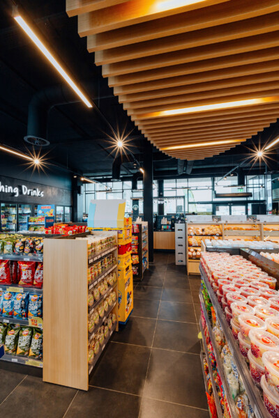 Louis Delhaize Groot Bijgaarden convenience store interior with Pitch shelving, bakery displays, and wooden ceiling with integrated lighting