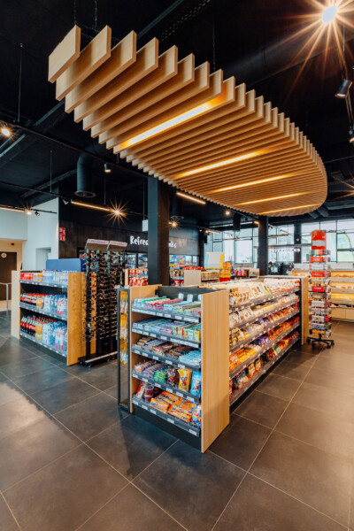 Louis Delhaize Groot Bijgaarden convenience store with wooden slatted ceiling, refrigerated display counter, and stocked shelving with beverages and snacks