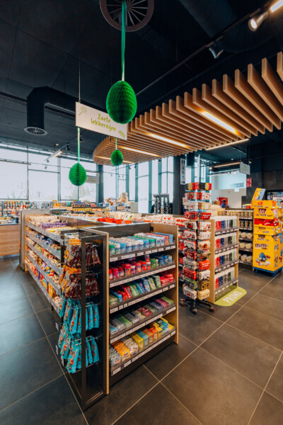 Candy and snack display with Pitch shelving, wooden ceiling slats, and green hanging decorations in specialty food retail