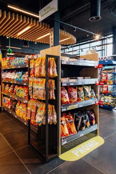 Snack and chip display with Pitch shelving in service station, showing yellow and red packaged products organized on multiple shelves