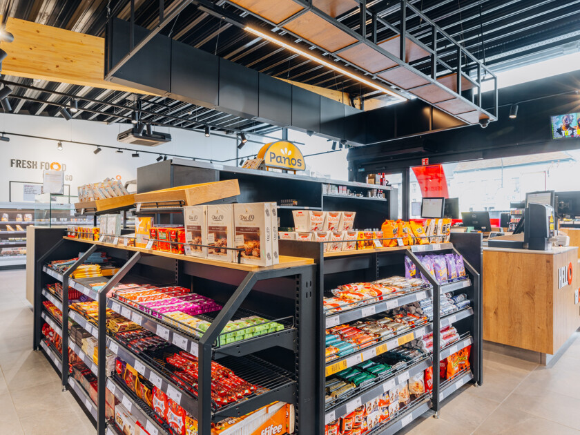 Pitch 41 shelving display with snack products in Q8 service station, featuring black metal gondola with wooden top accent
