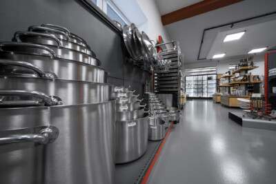 Stainless steel cookware and kitchenware display with nested pots, pans, and dish rack in professional retail showroom