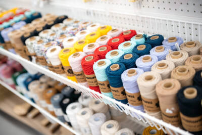 Colorful spools of thread and yarn organized on white retail shelf display