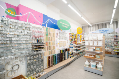 Craft supply retail store with pegboard wall displays, wooden sample holders, beaded necklace displays, and colorful branded signage for jewelry and hobby items